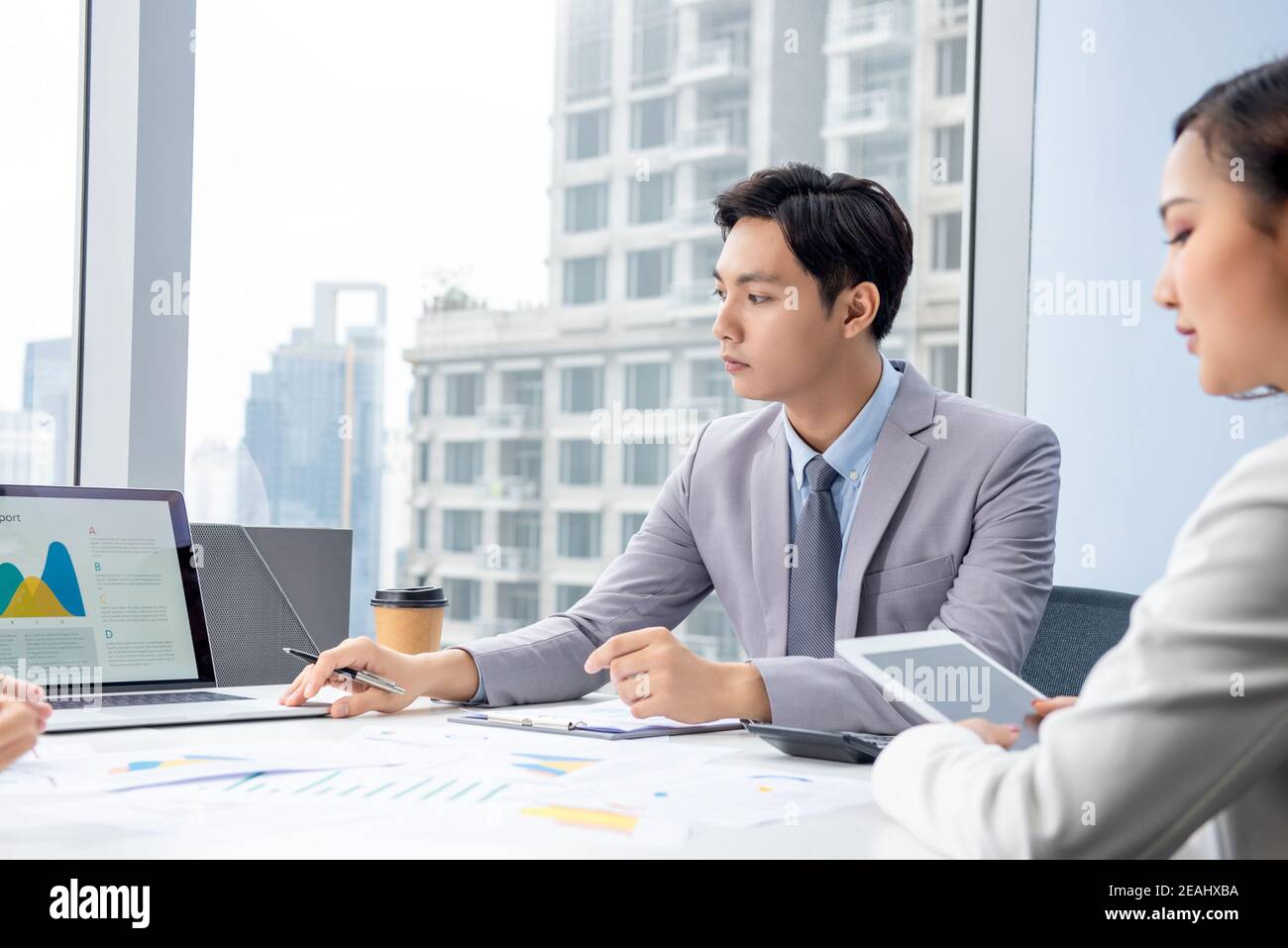 Young Asian businessman presenting corporate information chart on laptop computer in the meeting at city office Stock Photo