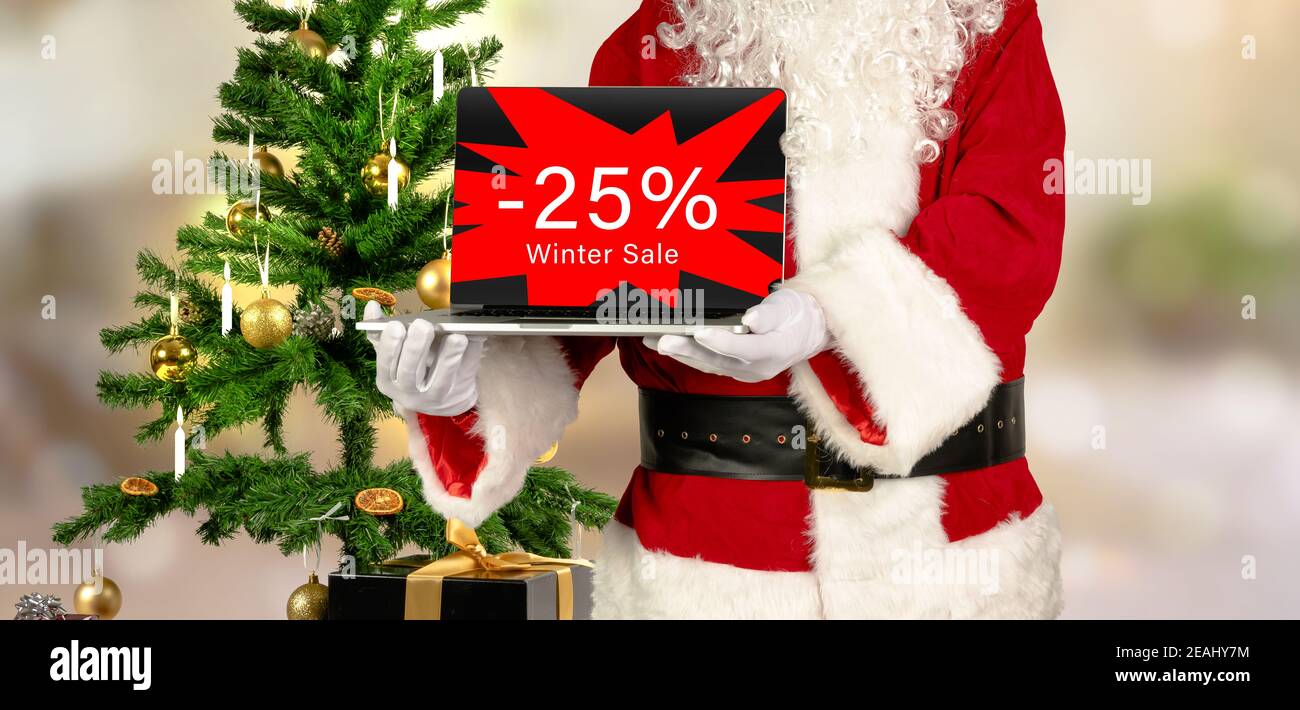 santa holds laptop in hand with 25 percent winter sale advertising Stock Photo