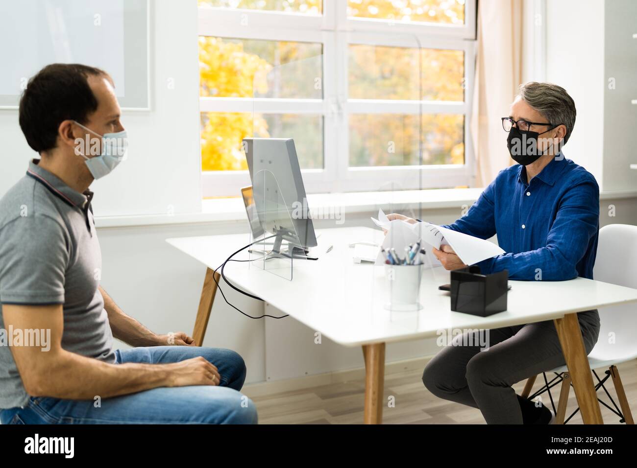 Insurance Consultant Or Lawyer In Bank With Sneeze Guard Stock Photo