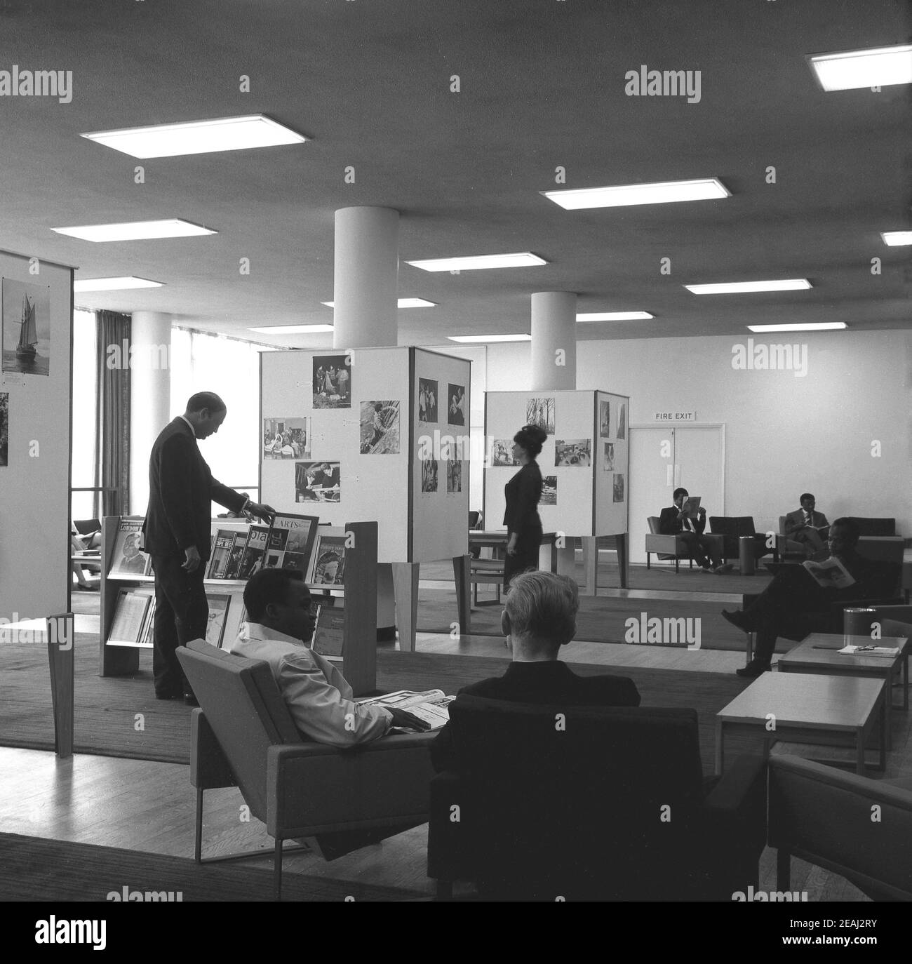 1960s, historical, people in the reception area or foyer at the  headquarters of the British Council, London, England, UK. Some are seated,  while a lady looks at the photos on display and