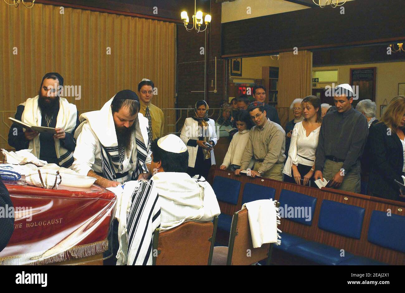 A Brit Milah ceremony takes place on the bimah of the synagogue in the Solihull, West Midlands, as the Mohel gives the traditional blessings as he commences the circumcision watched by the rabbi and family members. Stock Photo