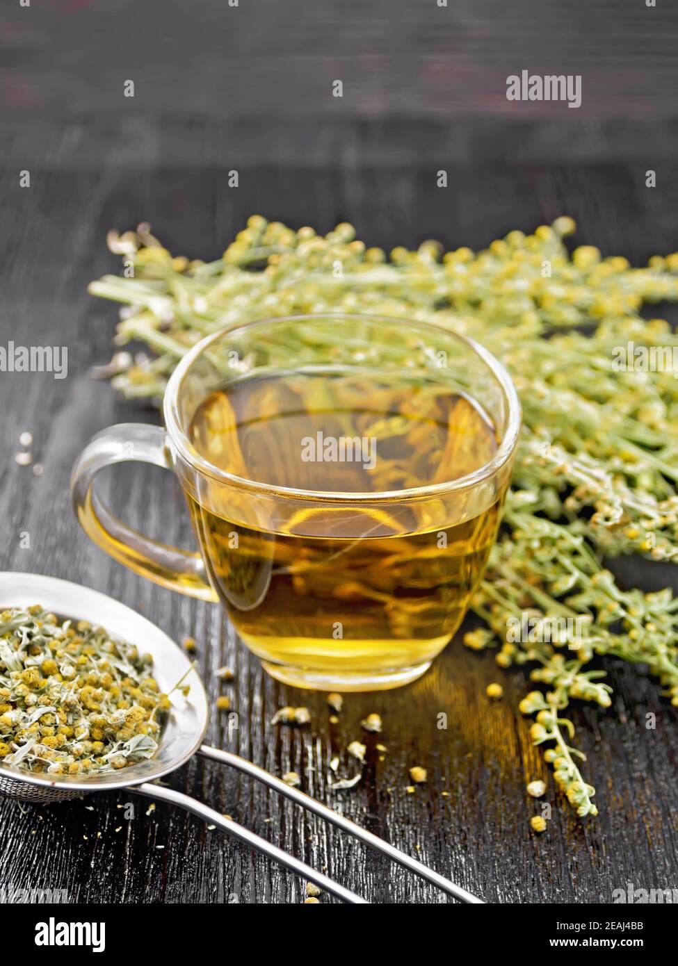Tea of gray wormwood in glass cup with strainer on black board Stock Photo