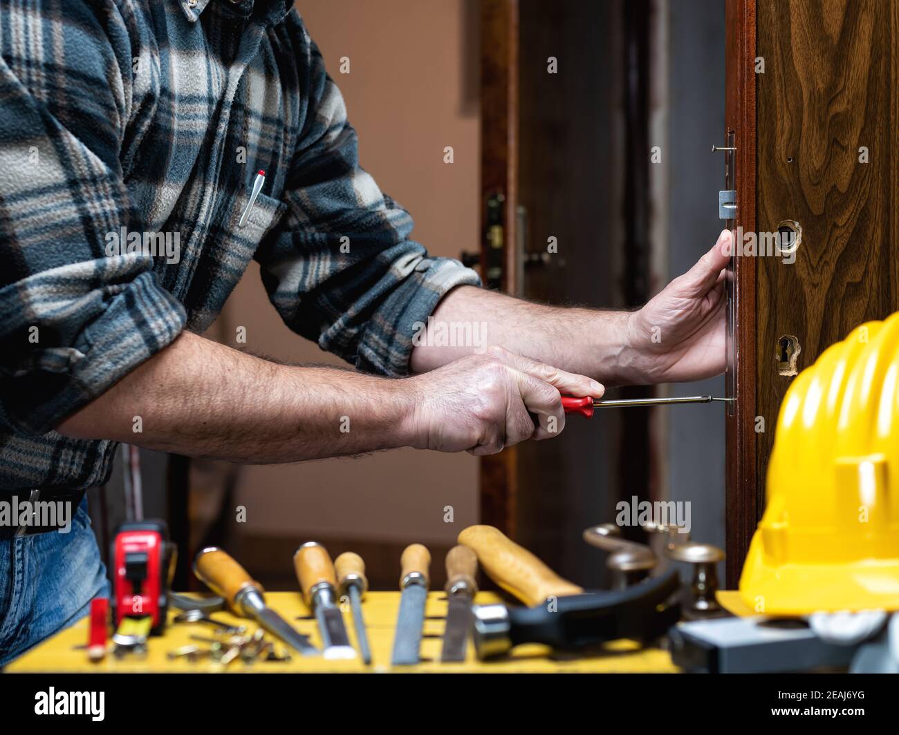 Carpenter at work repairs and installs the door lock. Carpentry Stock
