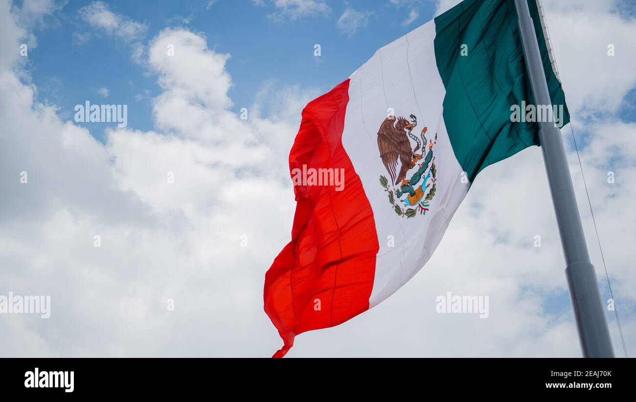 Mexican Flag Waving in the Wind and Cloudy Sky as the Background Stock Photo