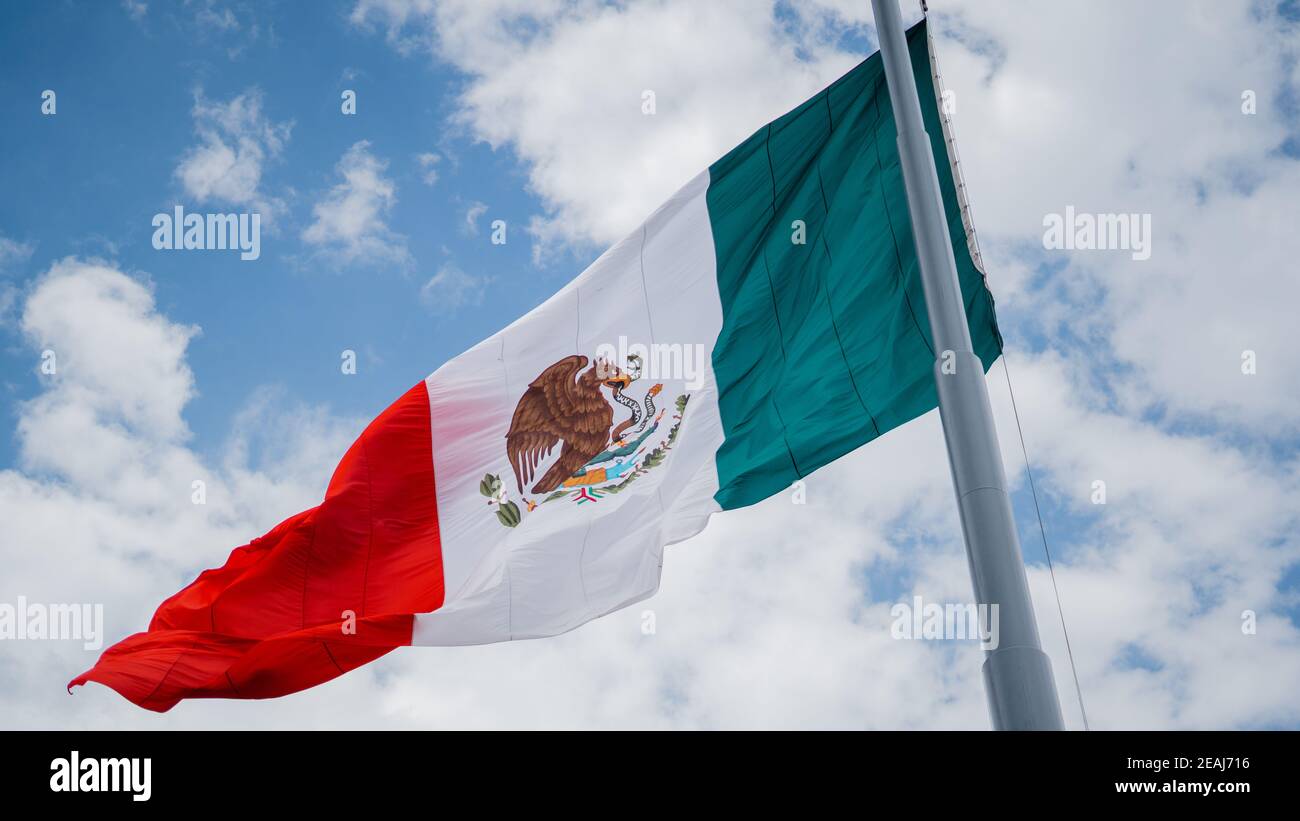 Mexican Flag Waving in the Wind with a Blue Sky in the Background Stock Photo