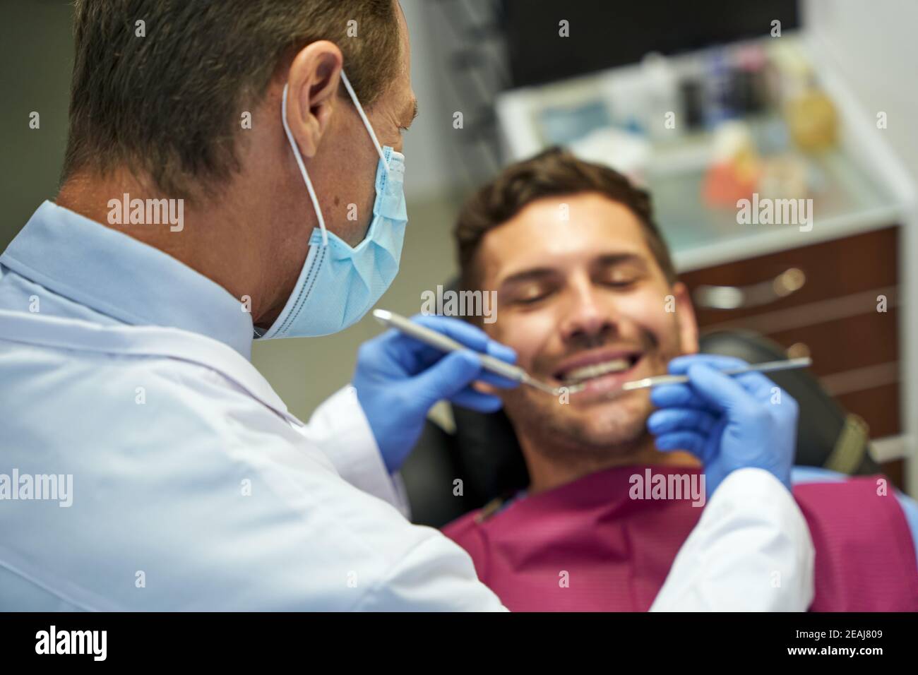 Professional dentist examining a young brunette man Stock Photo