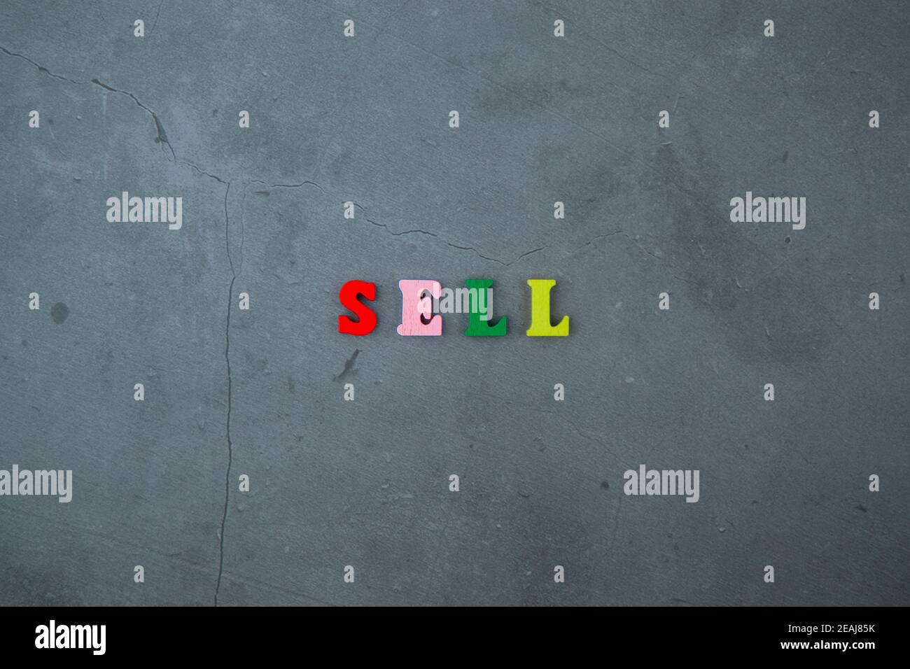 The multicolored sell word is made of wooden letters on a grey plastered wall background. Stock Photo