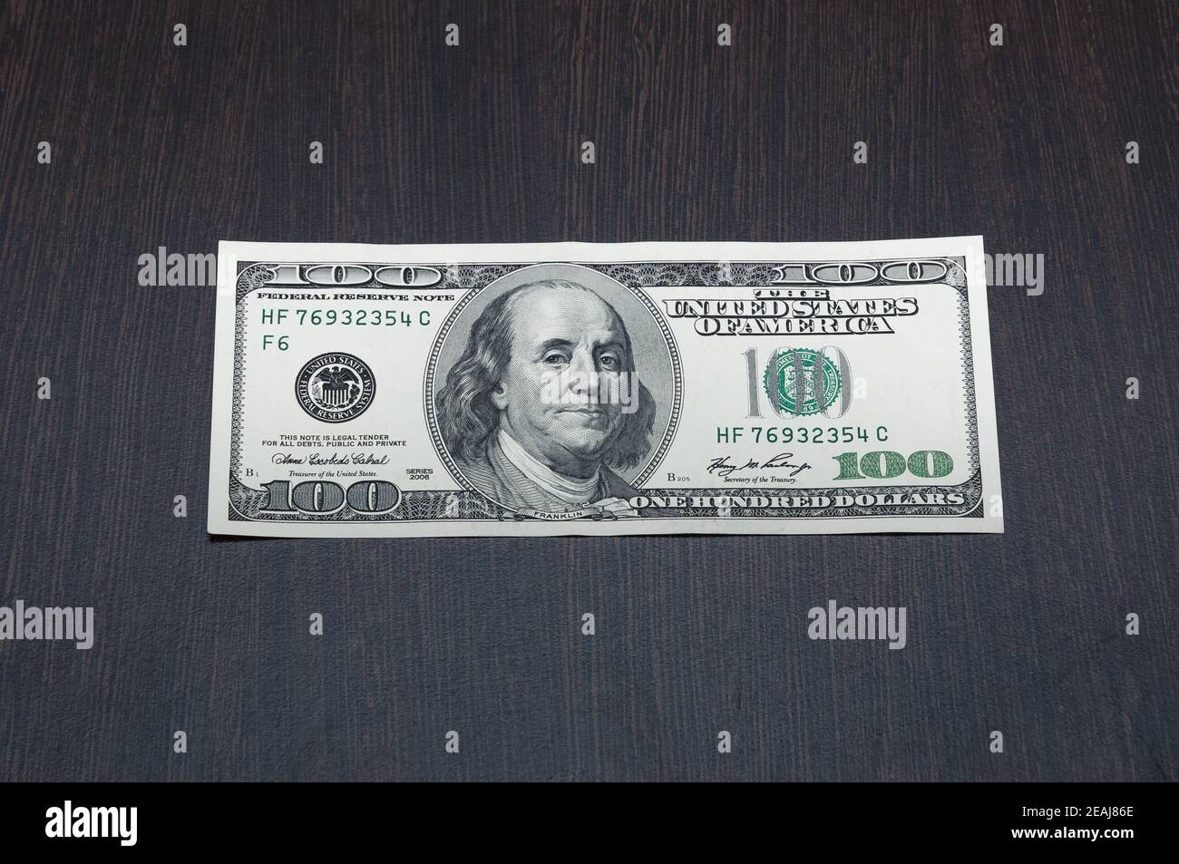 One hundred dollars. One bill on a wooden table. Frontal side. Stock Photo