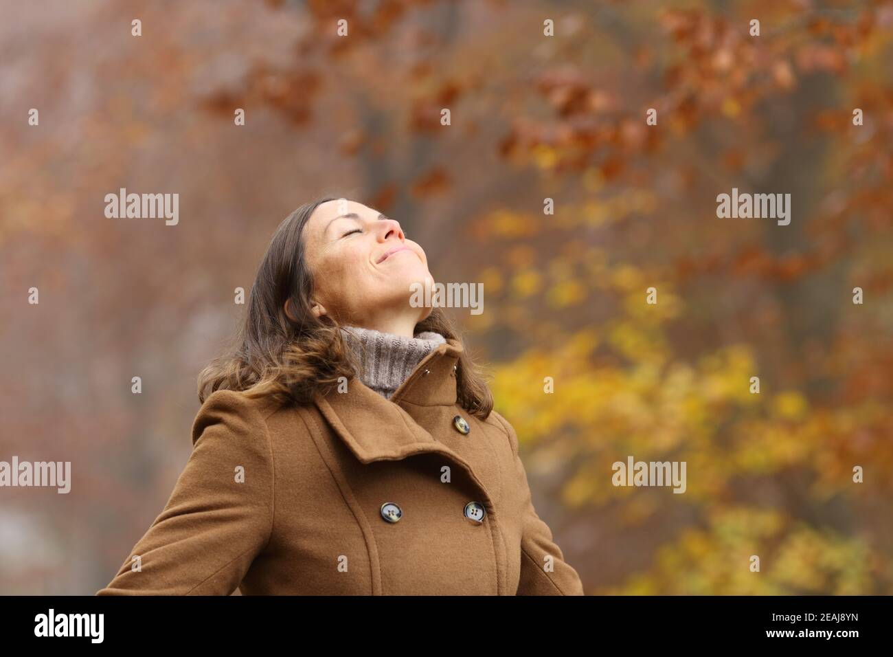 Middle aged woman breathing fresh air in a forest in autumn Stock Photo