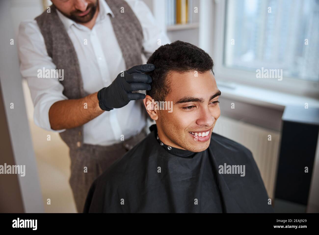 Man with shiny strong silky hair sitting on the chair while barber doing hair  cut in beauty parlor Stock Photo - Alamy