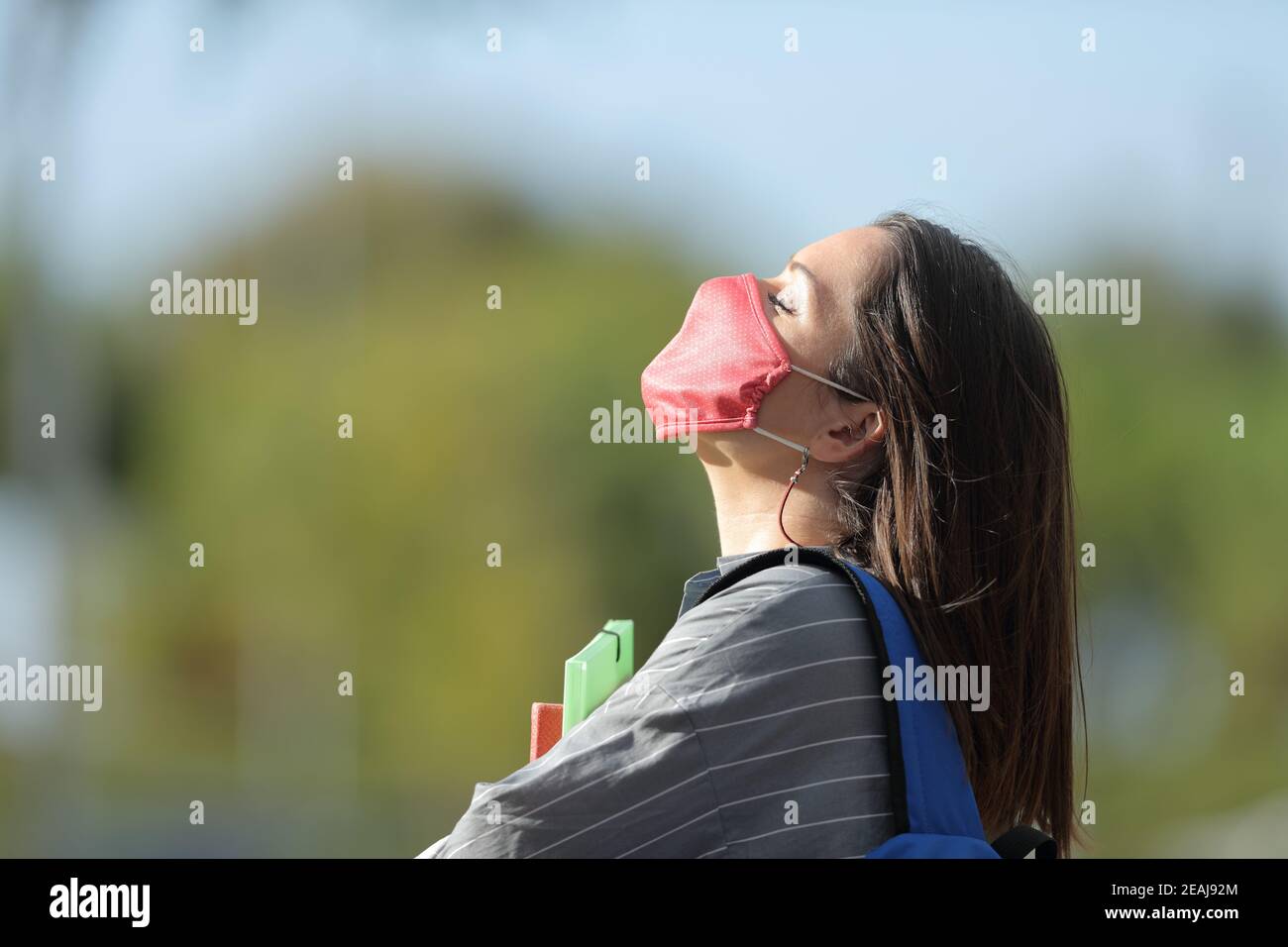 Student with mask breathing fresh air in a park Stock Photo
