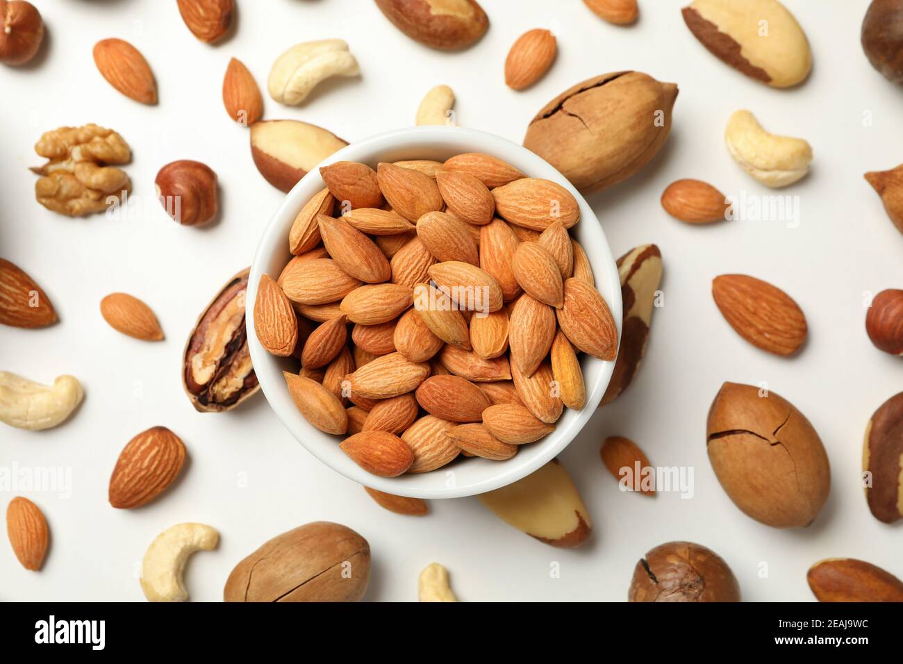 Bowl with apricot seeds and different nuts on white background Stock Photo