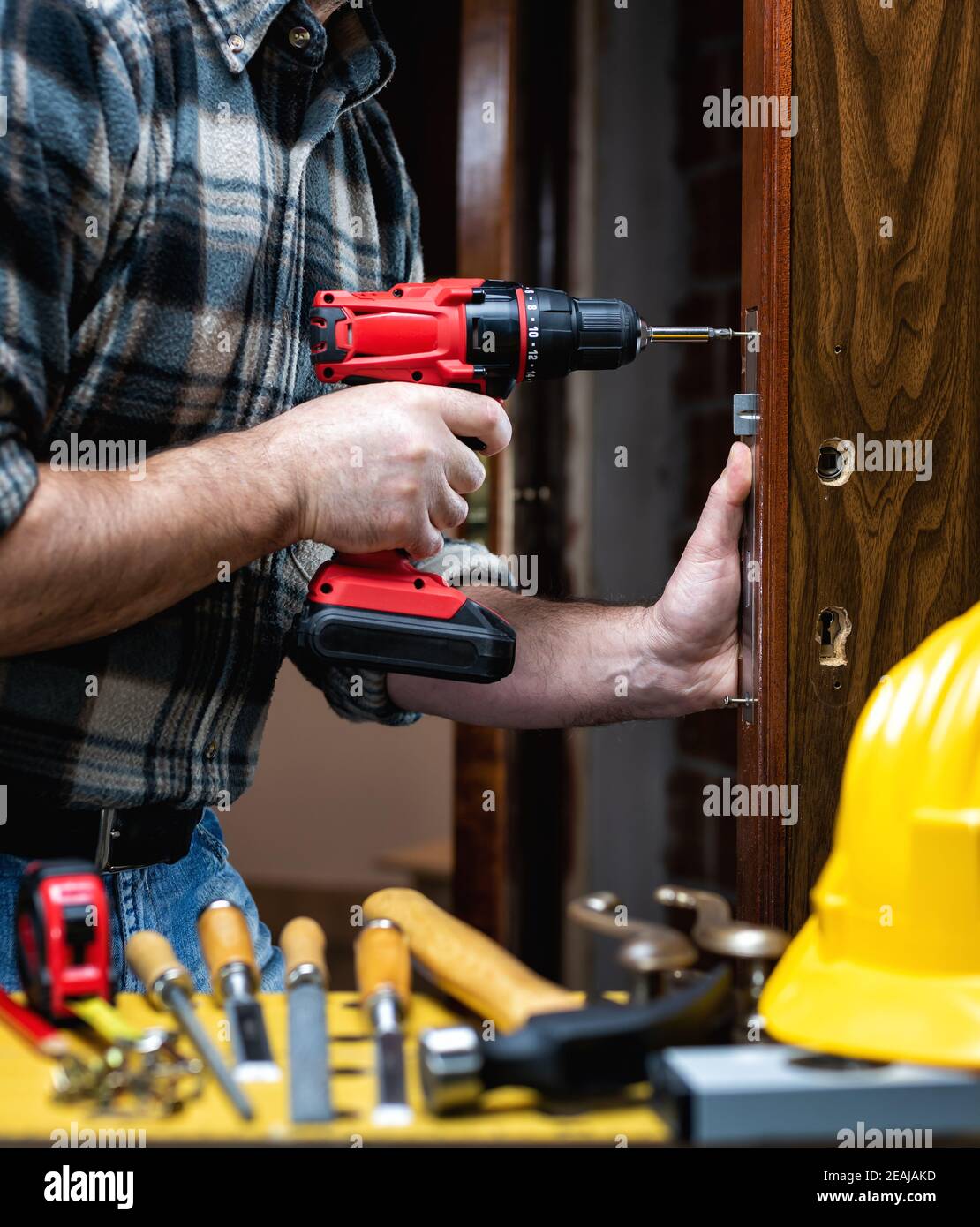 Carpenter at work repairs and installs the door lock. Carpentry Stock
