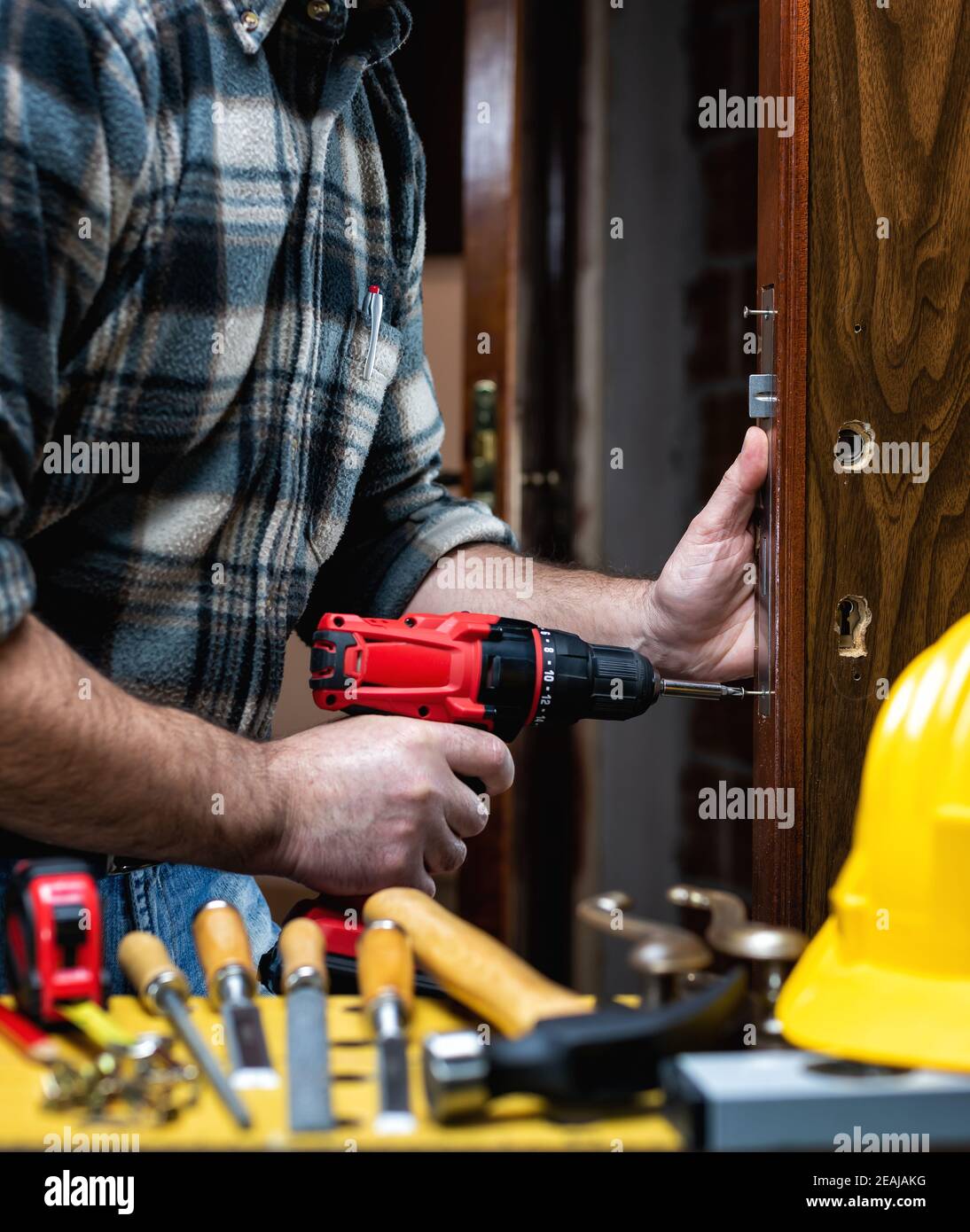 Carpenter at work repairs and installs the door lock. Carpentry. Stock Photo
