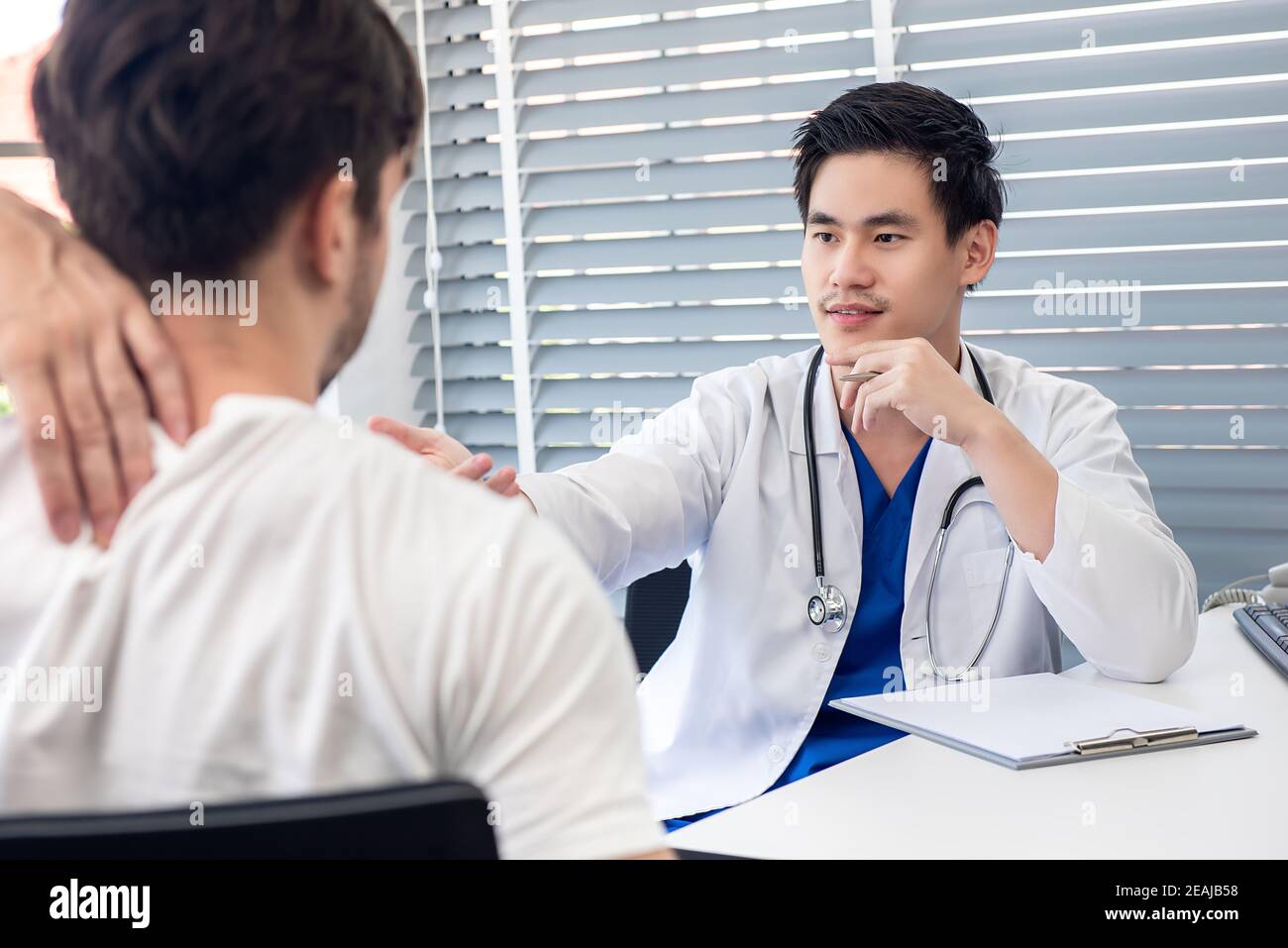 Young Asian male doctor giving medical checkup to his patient at the