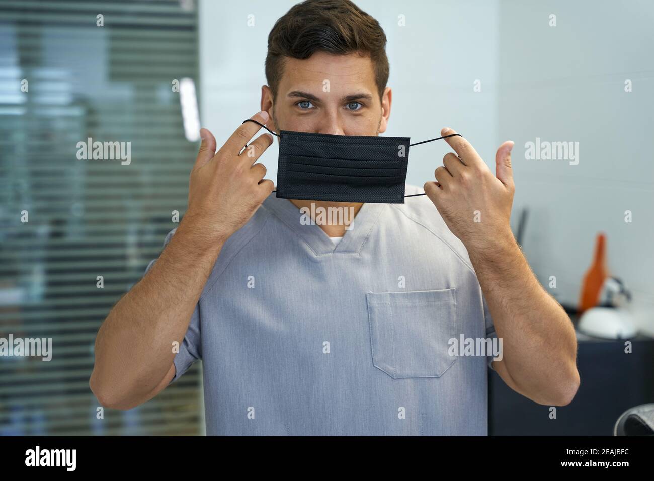 Handsome doctor demonstrating a way to put mask on Stock Photo