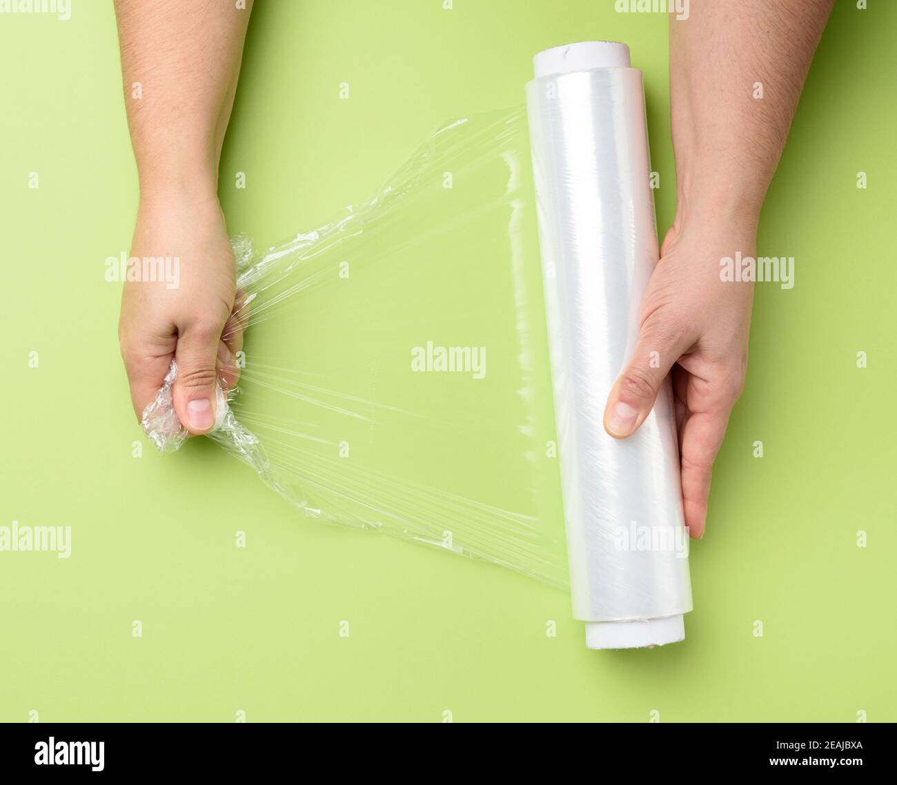 https://c8.alamy.com/comp/2EAJBXA/two-female-hands-hold-a-roll-of-transparent-cling-film-for-packaging-products-2EAJBXA.jpg
