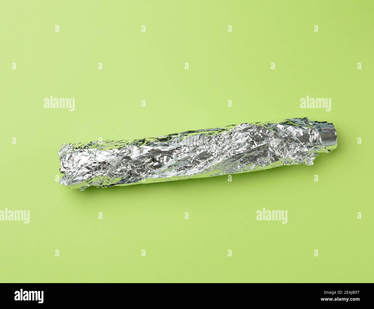 roll of gray foil for baking and packaging food on a green background Stock Photo