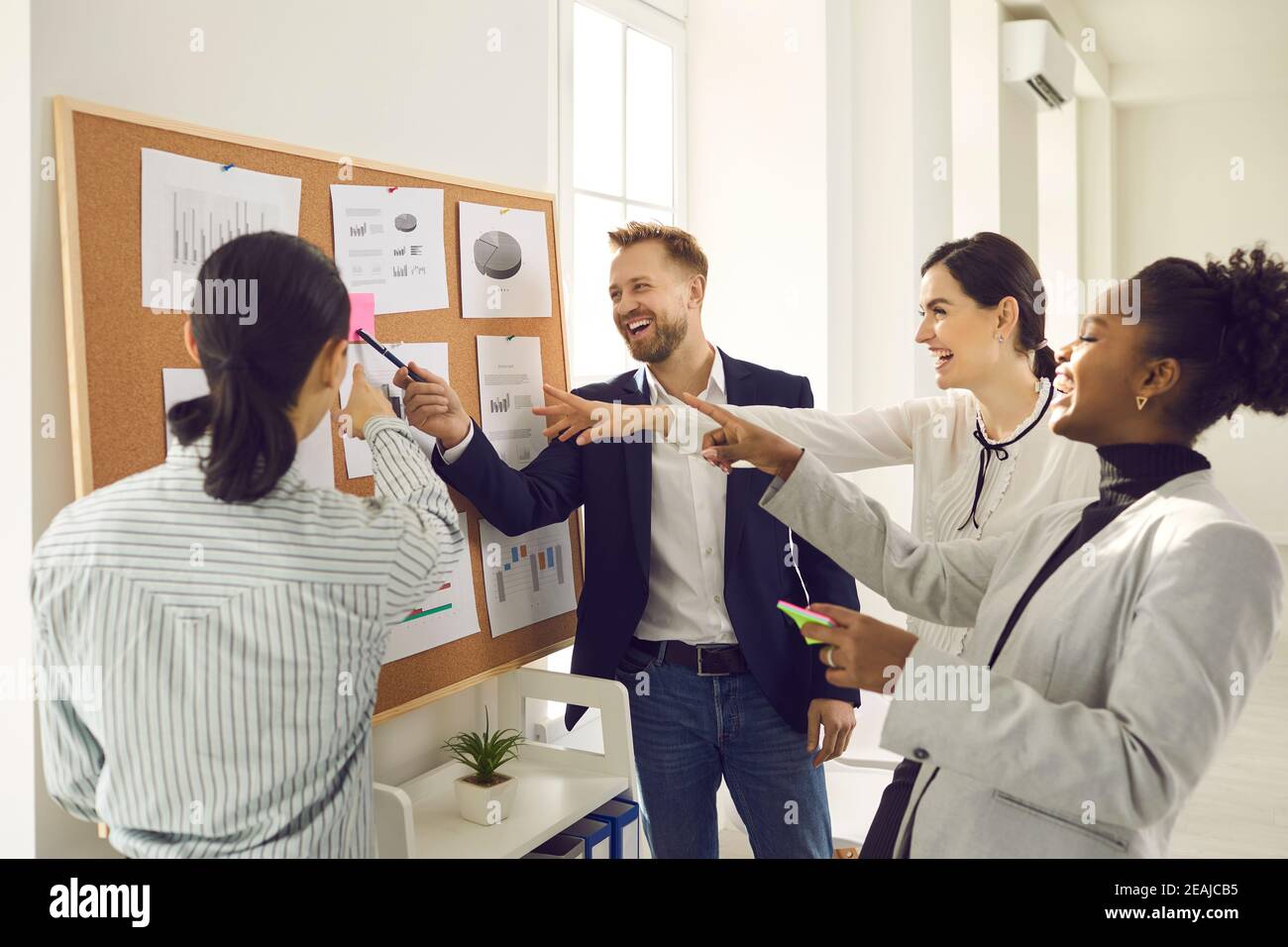 Group of multiethnic business partners laughing at reminder at board together Stock Photo