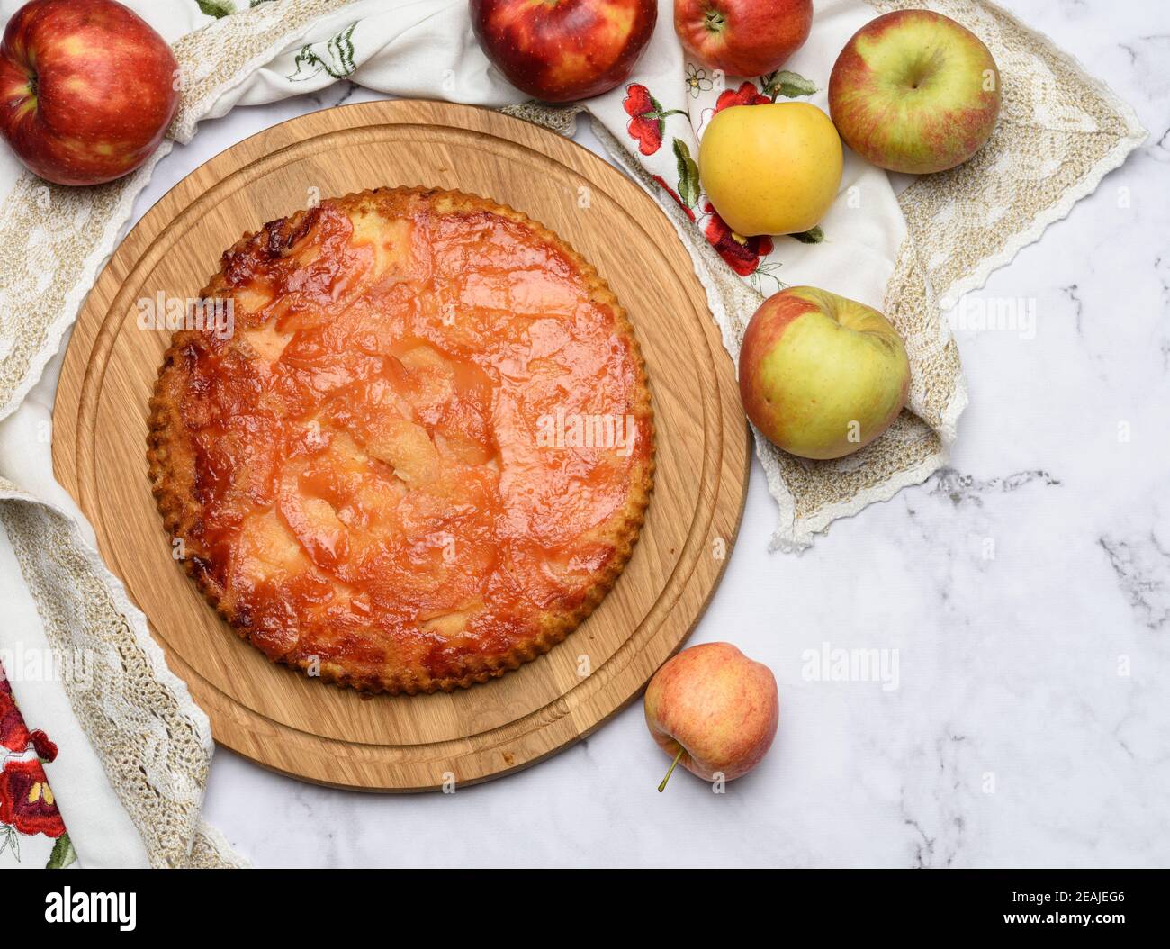 baked round apple pie on wooden board and fresh apples, top view Stock Photo