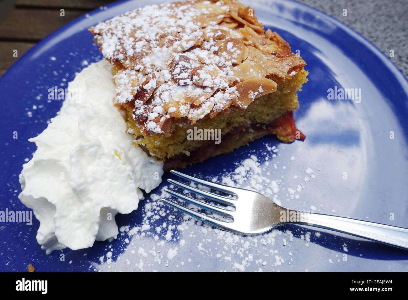 Pflaumenkuchen mit Sahne auf einem blauen Teller Stock Photo