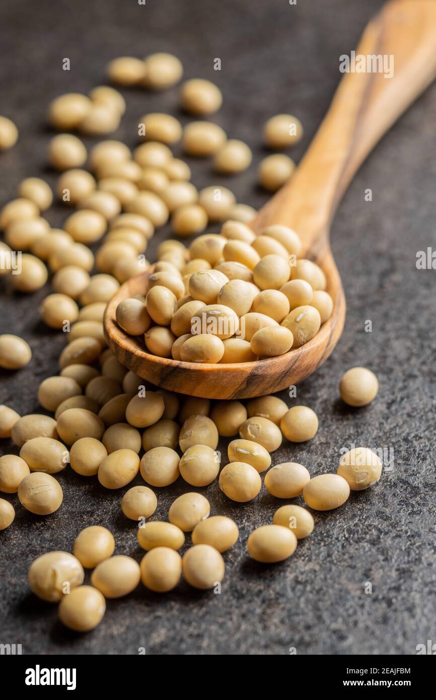 Dried soy beans in wooden spoon on black table. Stock Photo