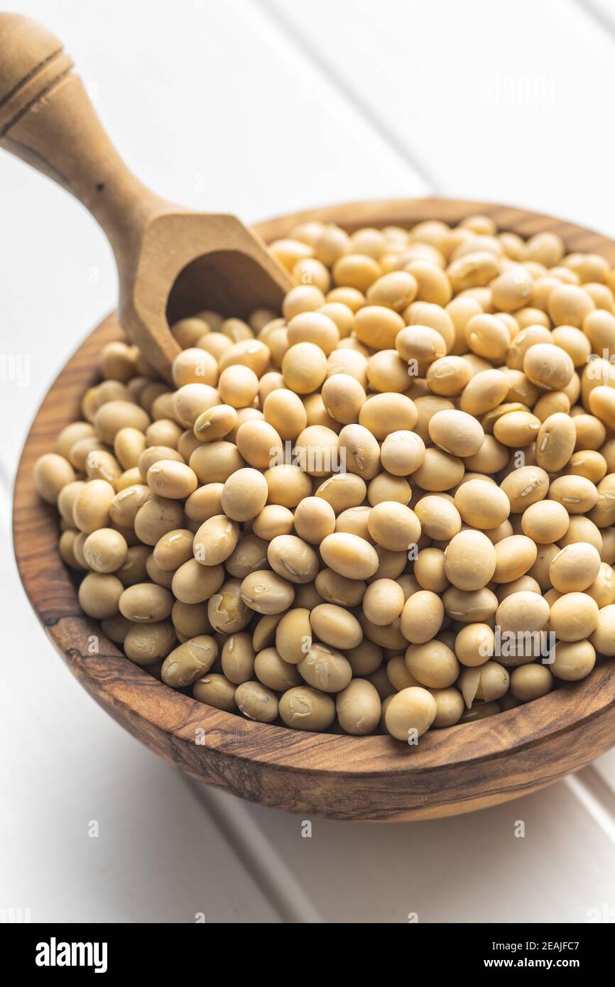 Dried soy beans in wooden bowl on white table. Stock Photo