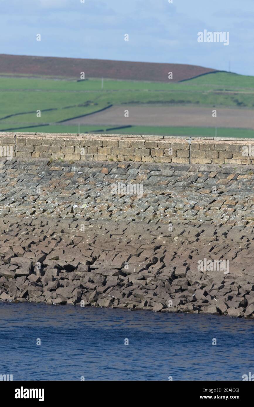Vertical image of a stone reservoir wall on a sunny day. Rural area Stock Photo