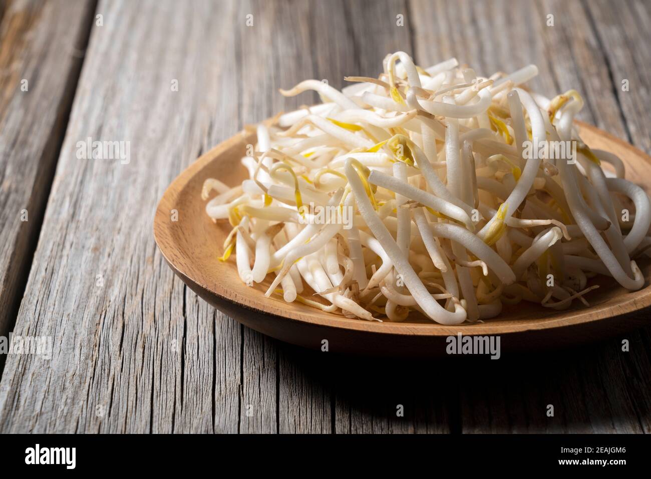 Bean sprouts in a wooden plate set against an old wooden background Stock Photo