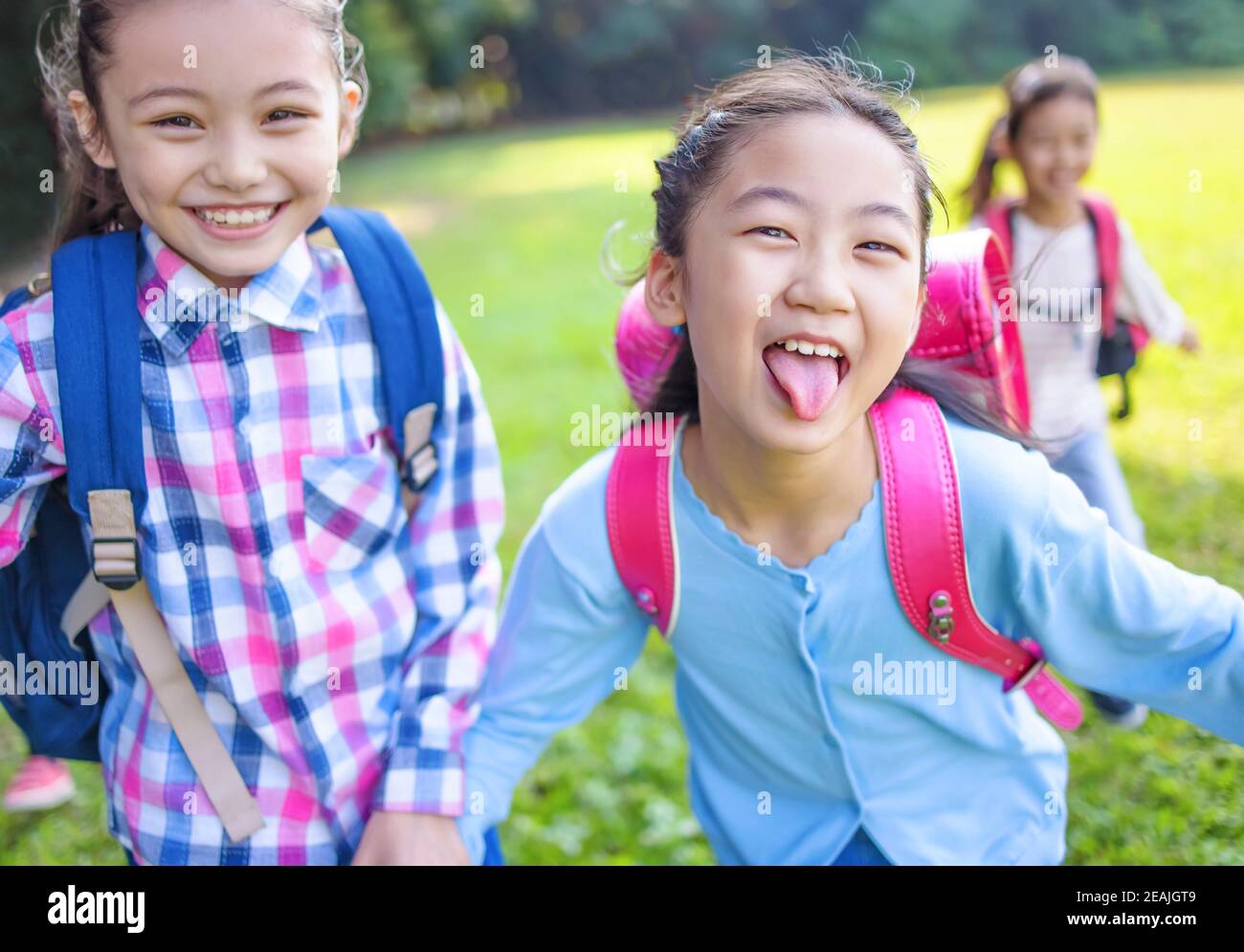 happy elementary school kids running on the grass Stock Photo