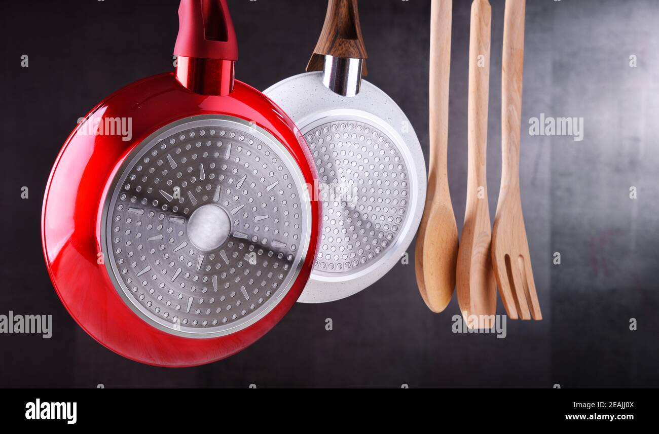 Two hanging frying pans and kitchen utensils Stock Photo Alamy