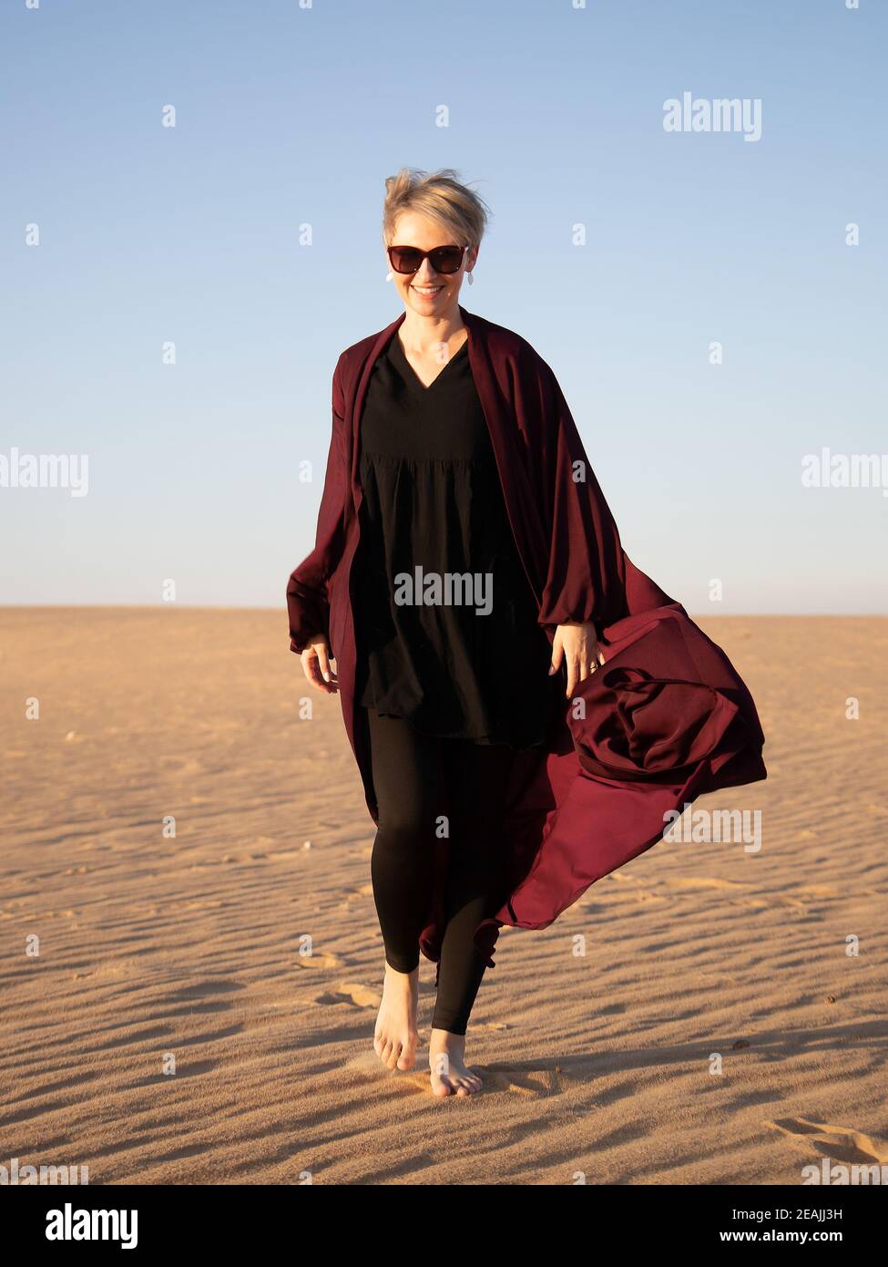 Young caucasian woman with dark red abaya in the Salisil desert in Saudi Arabia Stock Photo