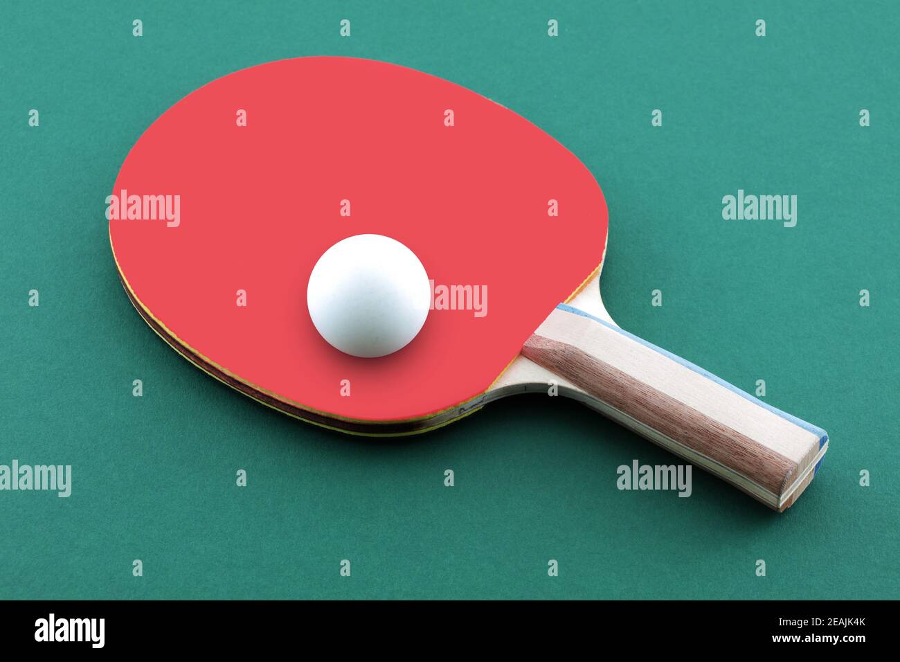 Green ping pong table with ball resting on a table tennis bat paddle Stock Photo