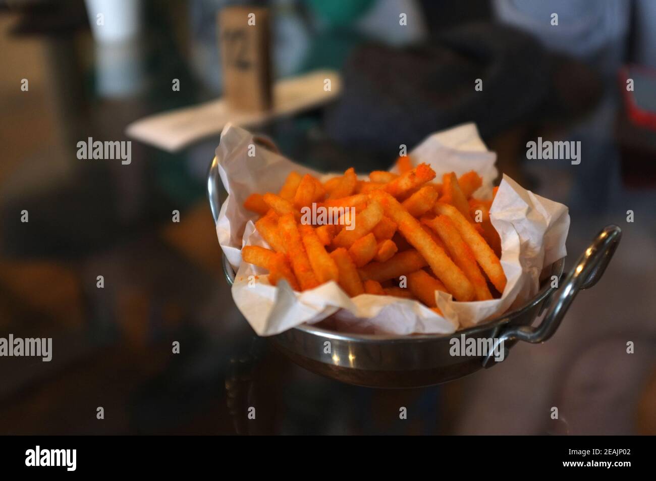 Hand holding French fries with chili cheese powder in a pan Stock Photo
