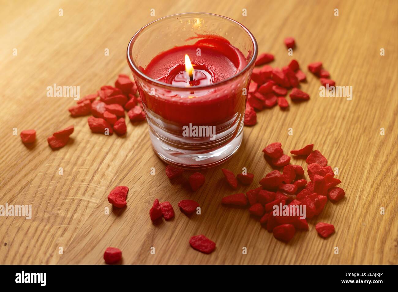 welness composition. red candle in glass on wooden table with red stones Stock Photo