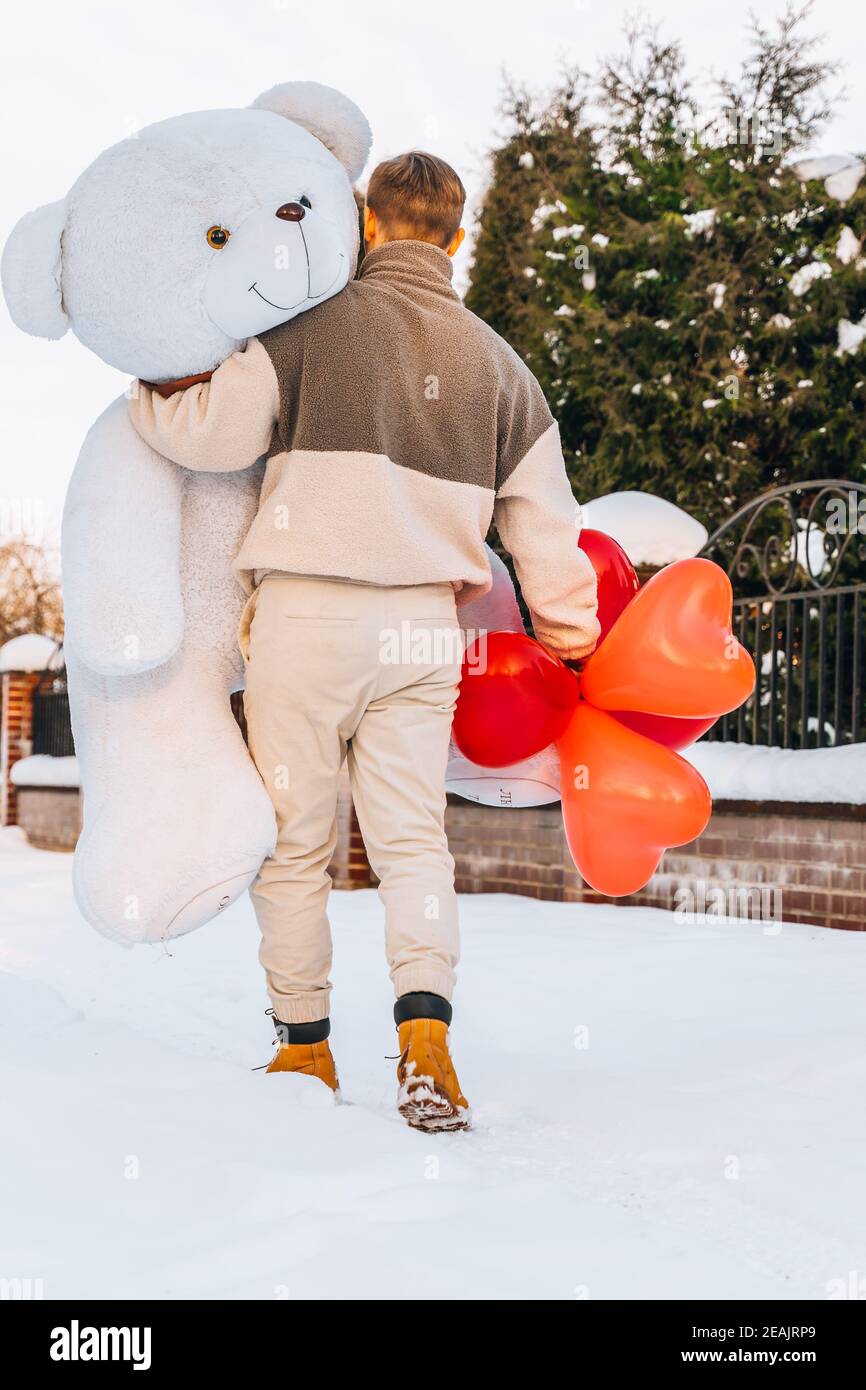 Young man from behind hugs holding big teddy bear soft toy gift ...