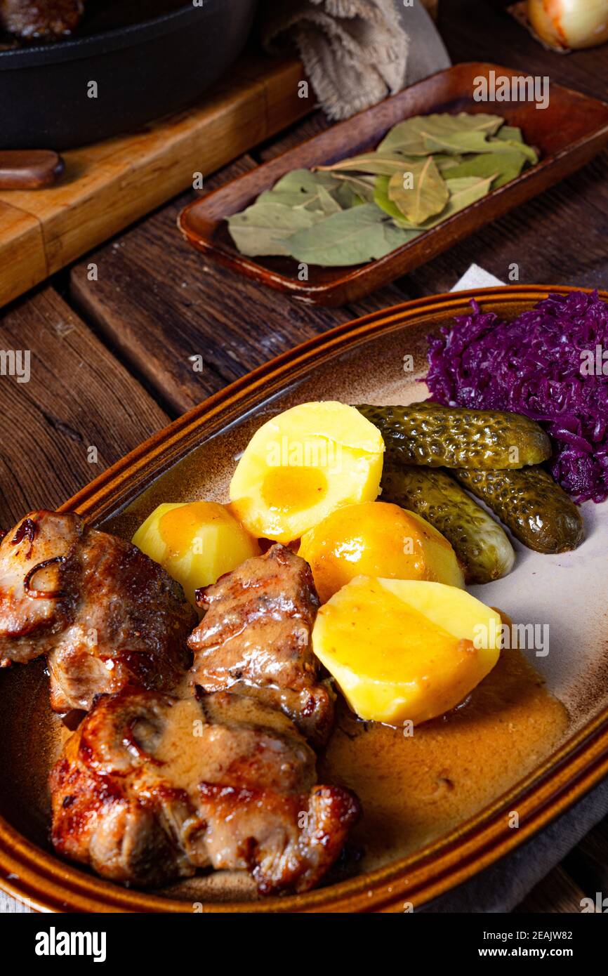 Rustic Snirtjebraten with red cabbage and cucumber Stock Photo