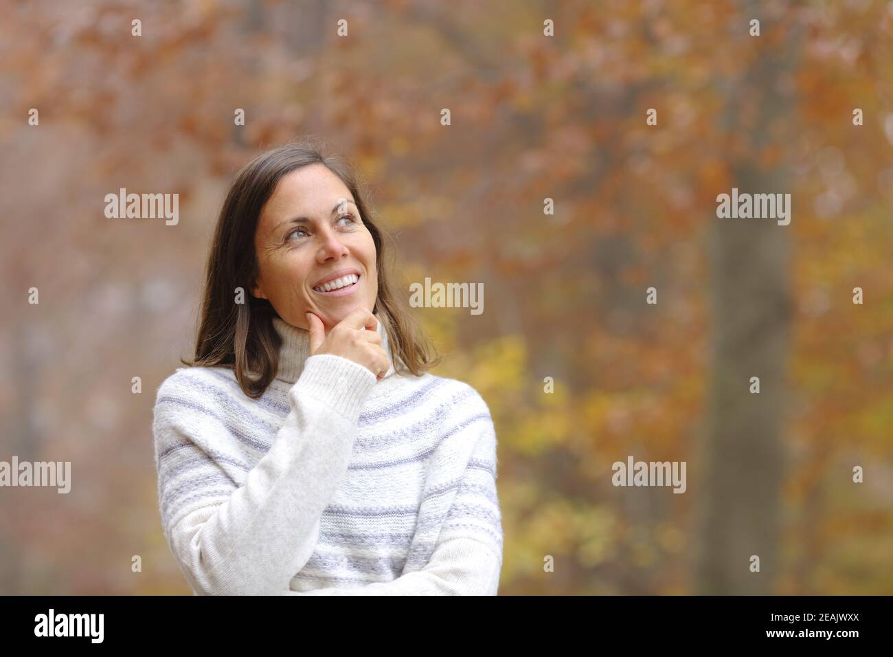 Pensive middle age woman in a forest in autumn Stock Photo