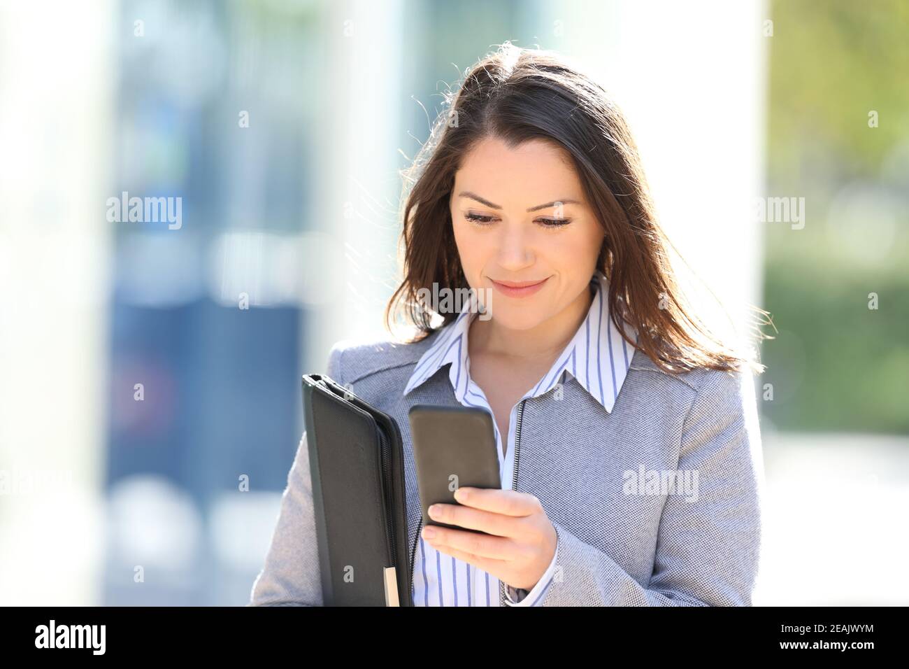 Executive checking smart phone while walks in the street Stock Photo