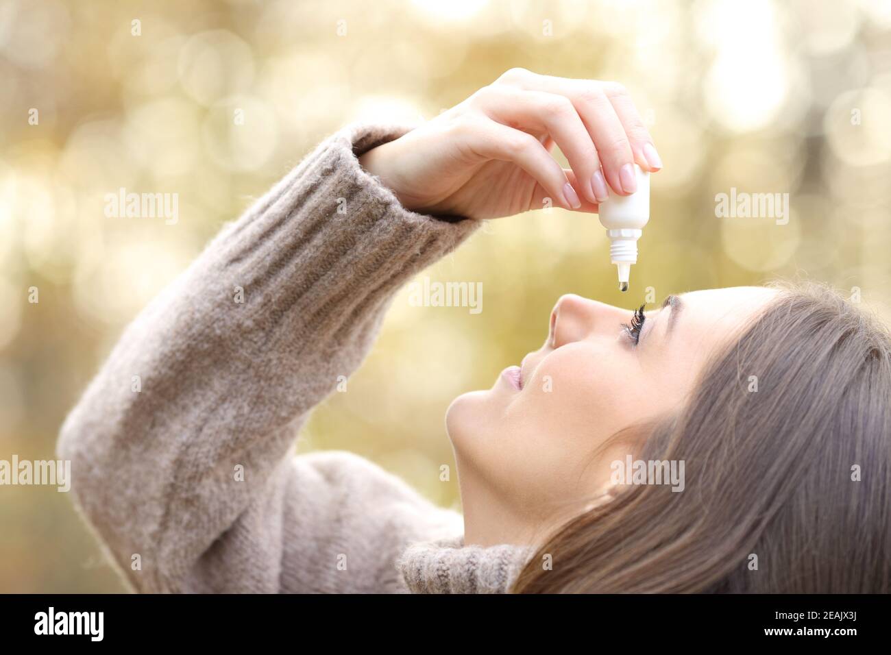 Woman with dry eyes applying artificial tear in winter Stock Photo