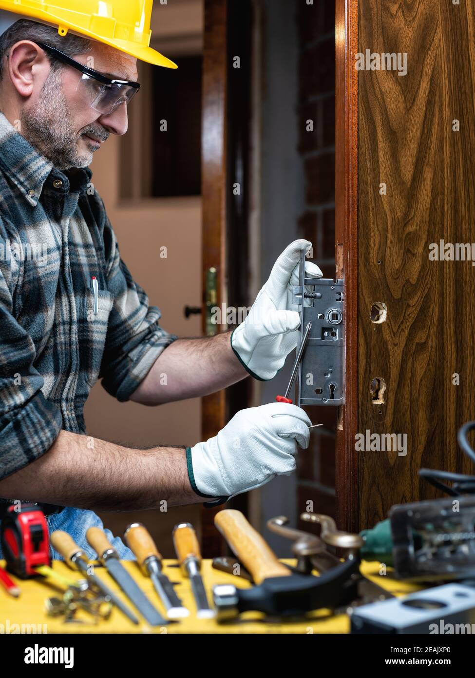 Carpenter at work repairs and installs the door lock. Carpentry Stock