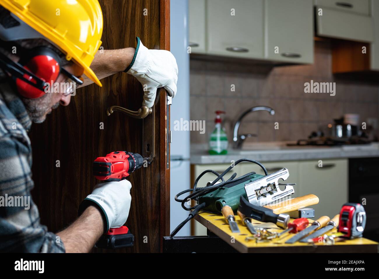 Carpenter at work repairs and installs the door lock. Carpentry Stock