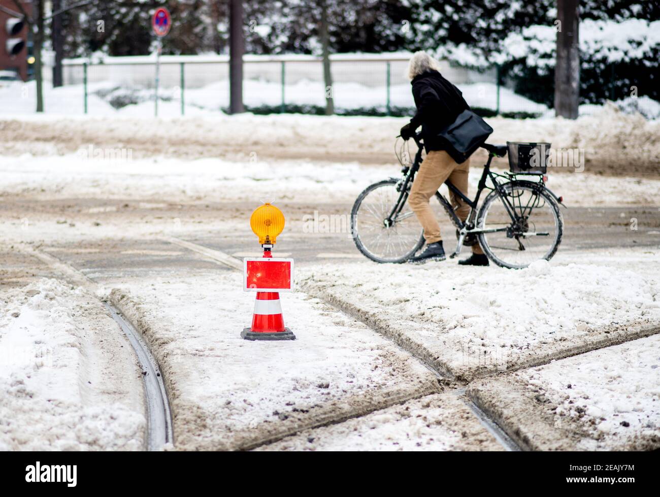 Hanover, Germany. 10th Feb, 2021. A cyclist stands on a street that is covered in snow, a track of the city railway in the Calenberger Neustadt is closed. Snow and ice continue to obstruct traffic in the state capital. Credit: Hauke-Christian Dittrich/dpa/Alamy Live News Stock Photo