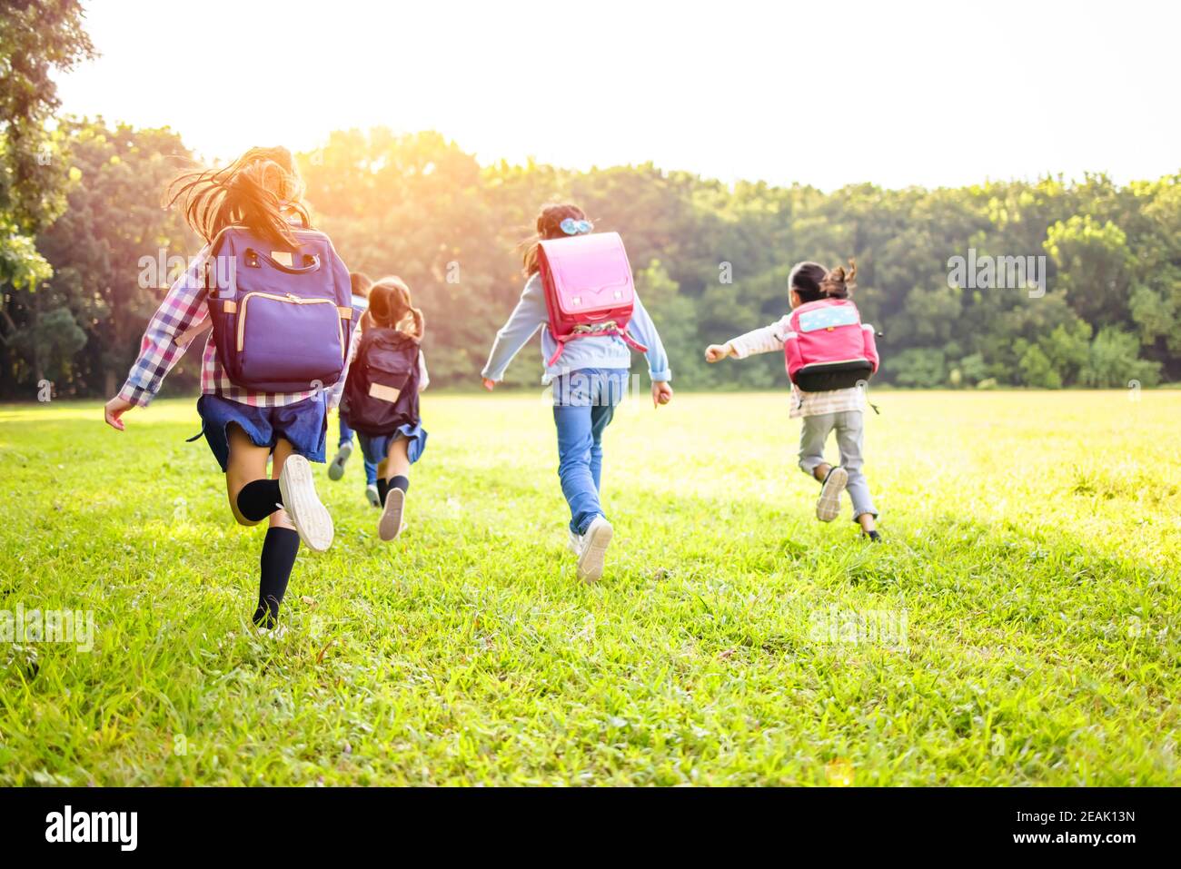rear view of elementary school kids running on the grass Stock Photo ...