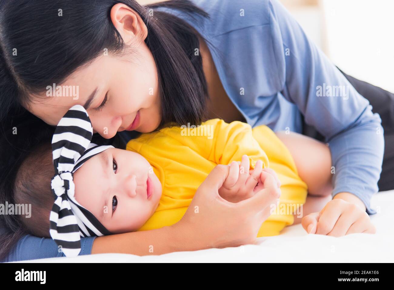 mother kissing her infant newborn baby in a white bed Stock Photo