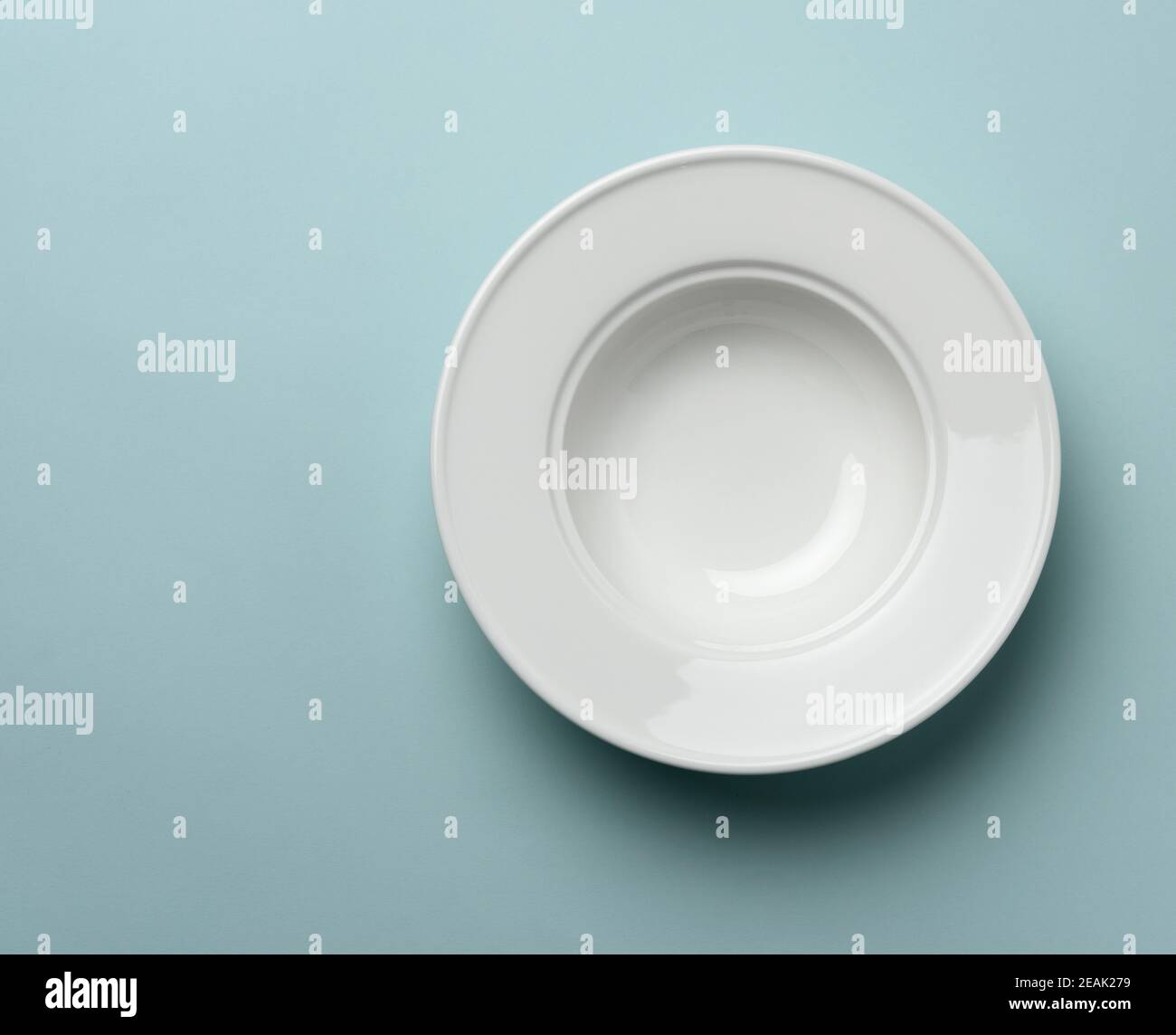empty white ceramic plate on blue background Stock Photo