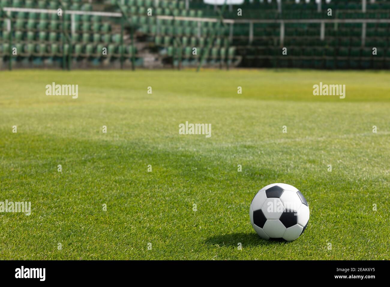 Classic Soccer Ball on Stadium Field. Row of Seats in the Stadium in the Background. Football Arena Seating Area in the Background. Grass Football Pit Stock Photo