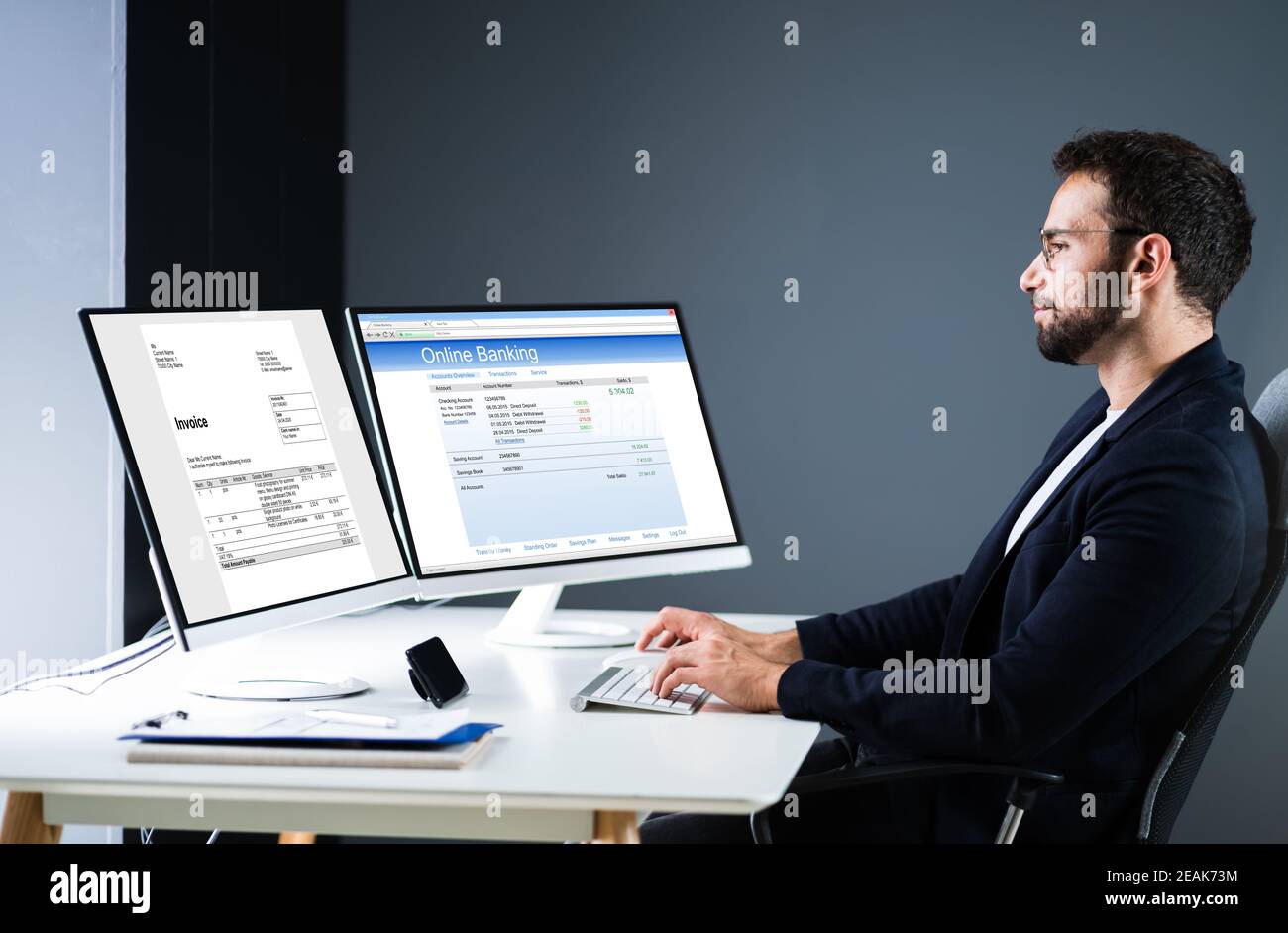 Young Businessman Looking At Invoice While Doing Online Banking Stock Photo