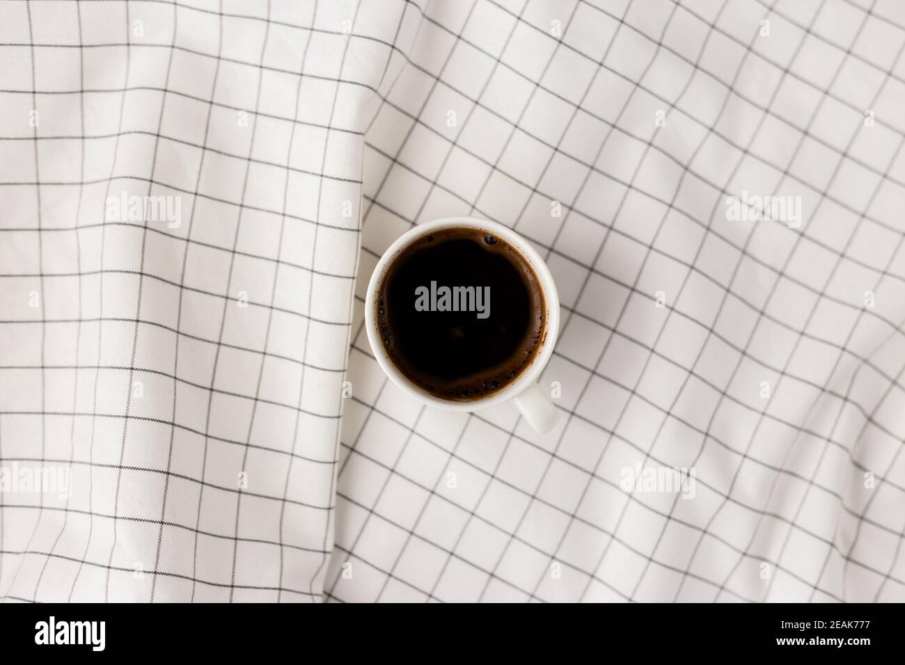 Cup of coffee cup on white checkered cloth background. Flat lay, top view, copy space. Minimal style concept Stock Photo