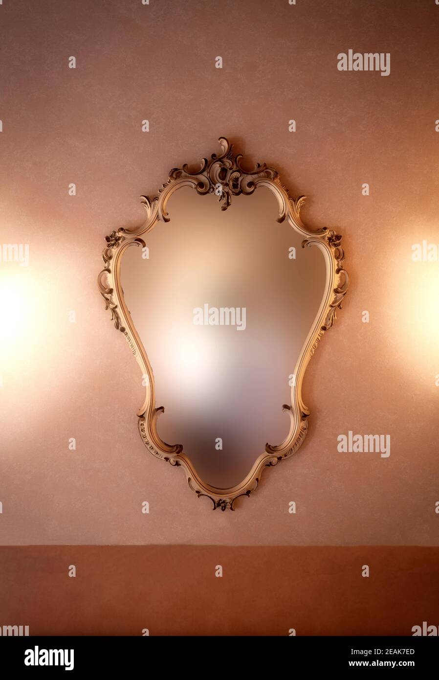 Old fashioned luxury gold colored frame mirror antique design, hanging on vintage wall background texture, blurred mirror, copy space Stock Photo